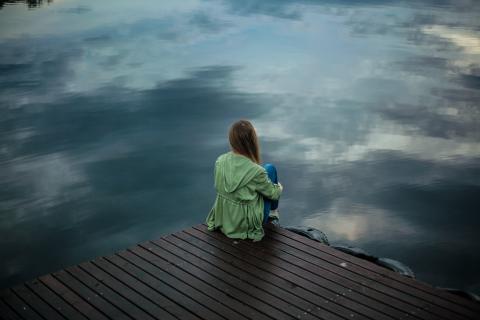 woman sitting on a dock looking out at water