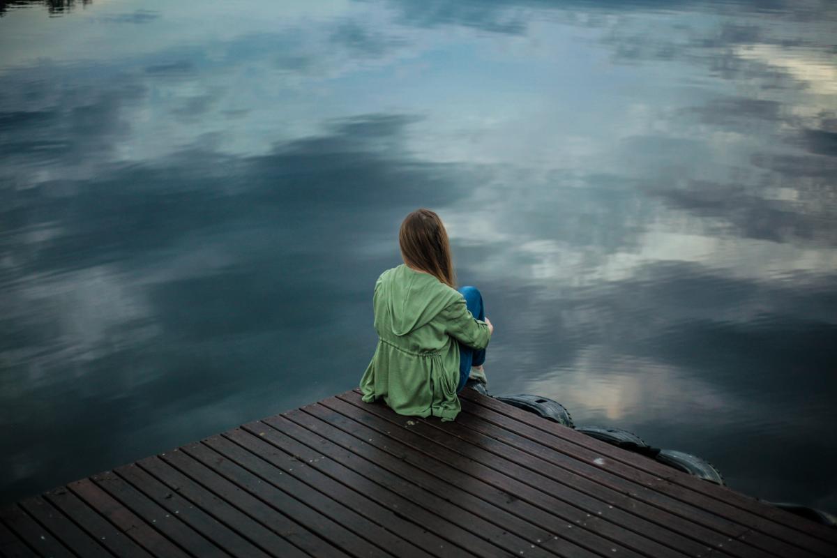 woman sitting on a dock looking out at water